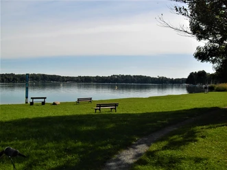 Gedenkstele, Ligewiese und Sitzbänke mit dem Blick auf den Schwielochsee