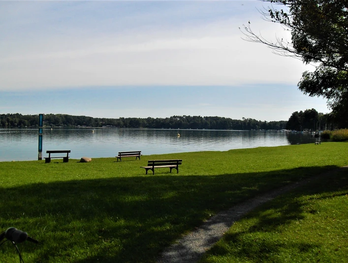 Gedenkstele, Ligewiese und Sitzbänke mit dem Blick auf den Schwielochsee
