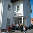 Außenansicht Hotel Papenbreer Weiße, zweistöckige Hotelfassade mit Blumenarrangements im Eingangsbereich bei sonnigem Wetter.