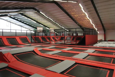 Jump´n Kick innen_Gemeinde Rhauderfehn Große Indoor-Trampolinhalle mit roten und schwarzen Trampolinen und Basketballkörben an der Wand