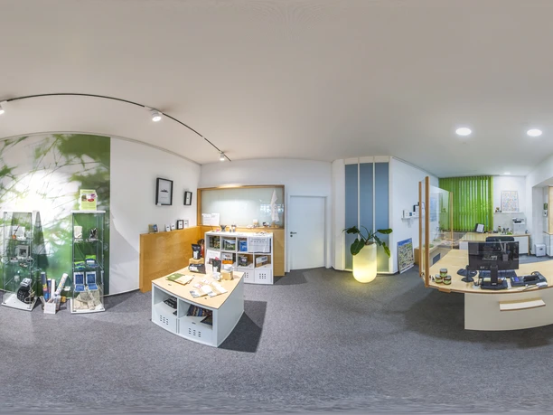 Empfangsbereich eines modernen Büros mit Infomaterial, Theke und offenen Regalen in heller Atmosphäre.