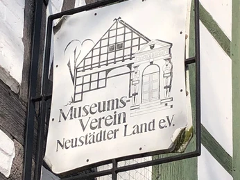 Museum zur Stadtgeschichte Das Bild zeigt ein Schild des Museumsvereins Neustädter Land e.V. an einem Fachwerkgebäude.