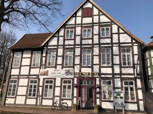 Fachwerkgebäude mit weißer Fassade und braunen Holzbalken, Eingangstür mit Museumsaufschrift.