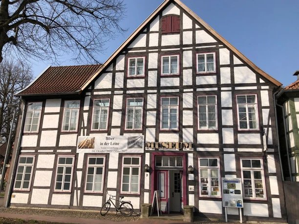 Fachwerkgebäude mit weißer Fassade und braunen Holzbalken, Eingangstür mit Museumsaufschrift.