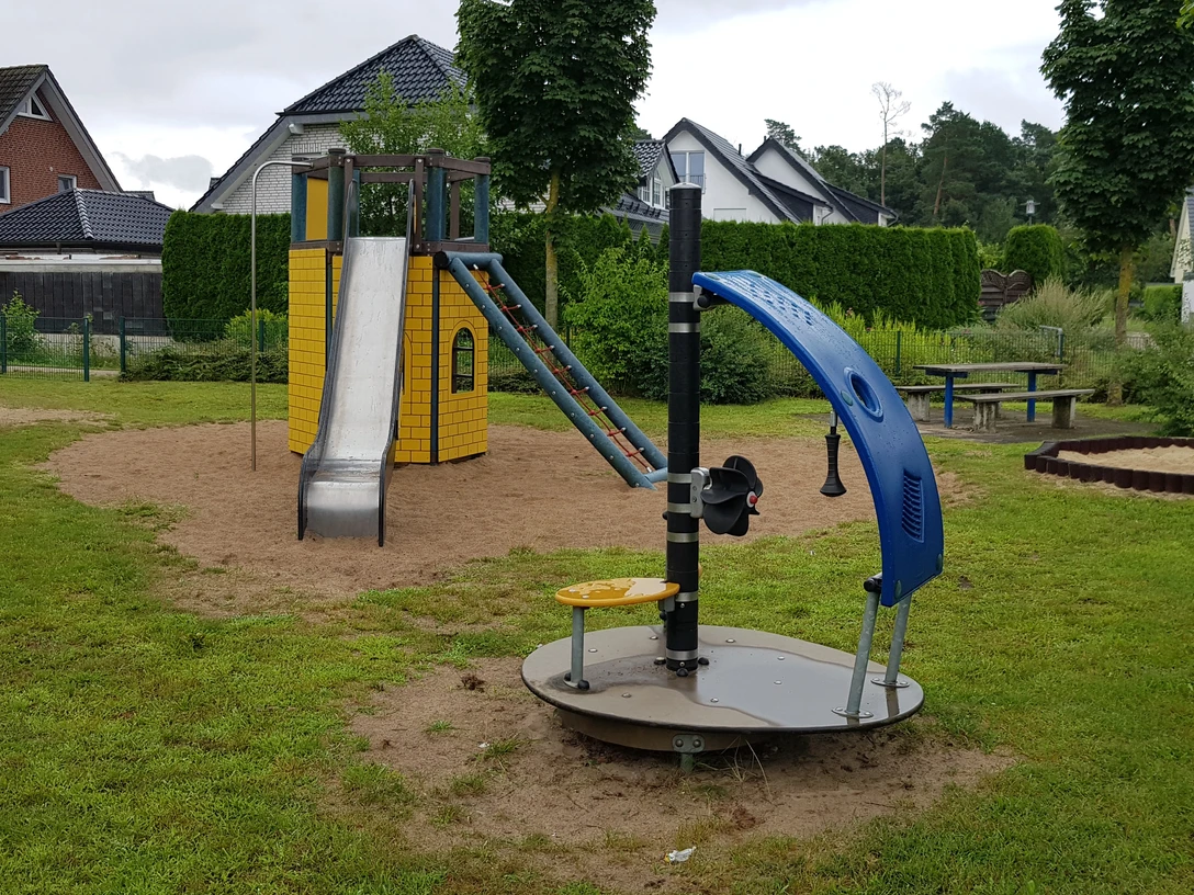 Spielplatz Gleiwitzer Straße Ein moderner Spielplatz mit Rutsche, Schaukeln und Drehscheibe, umgeben von Häusern und Grün.