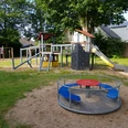 Spielplatz Mörikestraße Kinderspielplatz mit Sandboden, Rutsche, Klettergerüst und Karussell, umgeben von grünen Bäumen.