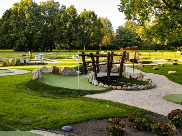 Minigolfanlage-pietzmoor-foto_ccbysa_foto©adventure-schnucken-golf-min.jpg Die Minigolfanlage in Pietzmoor zeigt grüne Bahnen, umgeben von Kieswegen und Bäumen.