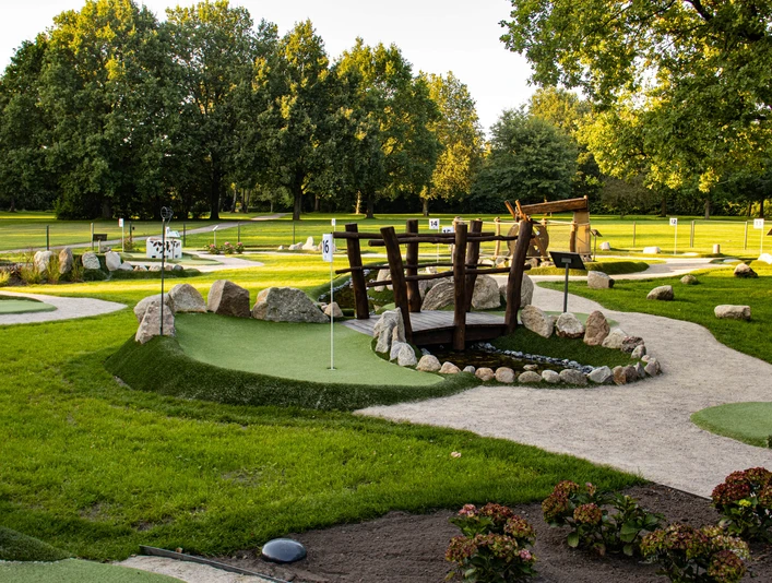 Minigolfanlage-pietzmoor-foto_ccbysa_foto©adventure-schnucken-golf-min.jpg Die Minigolfanlage in Pietzmoor zeigt grüne Bahnen, umgeben von Kieswegen und Bäumen.
