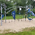 Spielplatz Posener Straße Modernes Klettergerüst auf Sandboden, umgeben von Bäumen, ideal für abenteuerlustige Kinder.