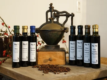 Espressoliköre Verschiedene Espressolikörflaschen stehen neben einer antiken Kaffeemühle, umgeben von Kaffeebohnen.