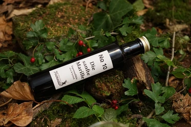 Espressolikör Espressolikörflasche auf Waldboden mit Blättern und roten Beeren, nahe Nordpolen aufgenommen.