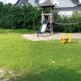 Spielplatz Katherine-Allfrey-Straße Spielplatz mit Rutsche, Klettergerüst und Wippspielzeug auf sandigem Boden, umgeben von Rasen.