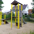 Spielplatz Amselweg Spielplatz in Wohngegend mit Rutsche und Klettergerüst auf Sandfläche, umgeben von Bäumen und Häusern.