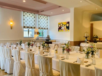 Kleiner Saal Haus Henkenjohann Elegantes, lichtdurchflutetes Restaurant mit stilvoll gedeckten Tischen und Blumenarrangement.
