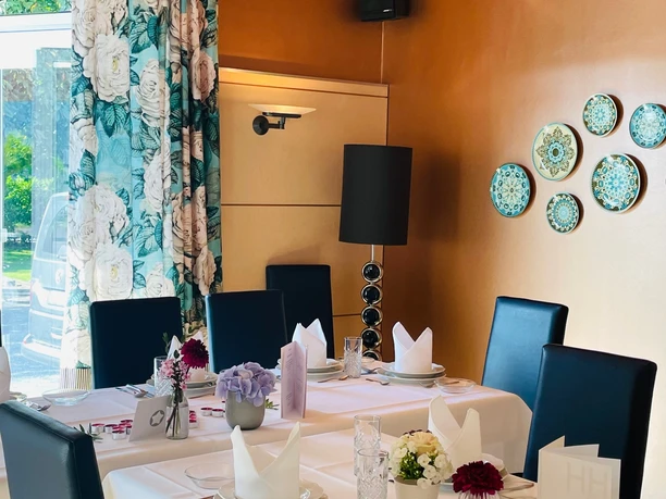 Restaurant Haus Henkenjohann Elegantes Restaurant mit geschmackvoll gedecktem Tisch, Blumenarrangements und stilvoller Wanddekoration.
