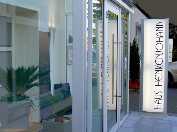 Eingang Haus Henkenjohann Eingangsbereich des modernen Bürogebäudes Haus Henkenjohann mit verglaster Fassade und Pflanzen.