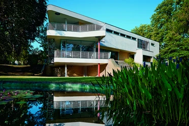 01_HausSchminke_Gartenansicht_vonNO_MSchroeder.jpg Moderne Architektur des Hauses Schminke mit Teich im Vordergrund.