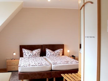 Helles Dachzimmer mit zwei Einzelbetten, modernem Dekor und indirekter Beleuchtung.