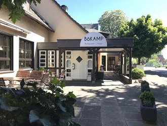 Gasthof Bökamp_Außenansicht2 Gemütlicher Eingangsbereich des Bökamp Restaurants und Hotels mit Sitzgelegenheiten im Freien.