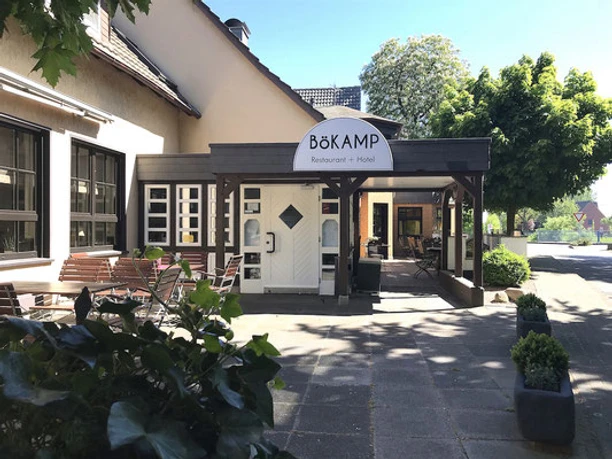 Gasthof Bökamp_Außenansicht2 Gemütlicher Eingangsbereich des Bökamp Restaurants und Hotels mit Sitzgelegenheiten im Freien.