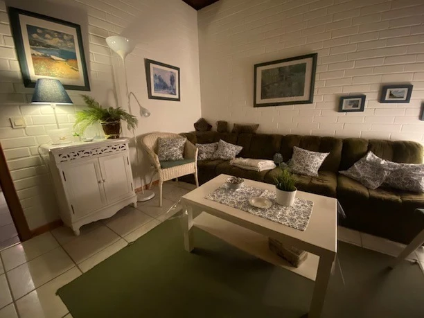 Gemütliches Wohnzimmer mit grüner Couch, weißen Möbeln und stimmungsvoller Beleuchtung.