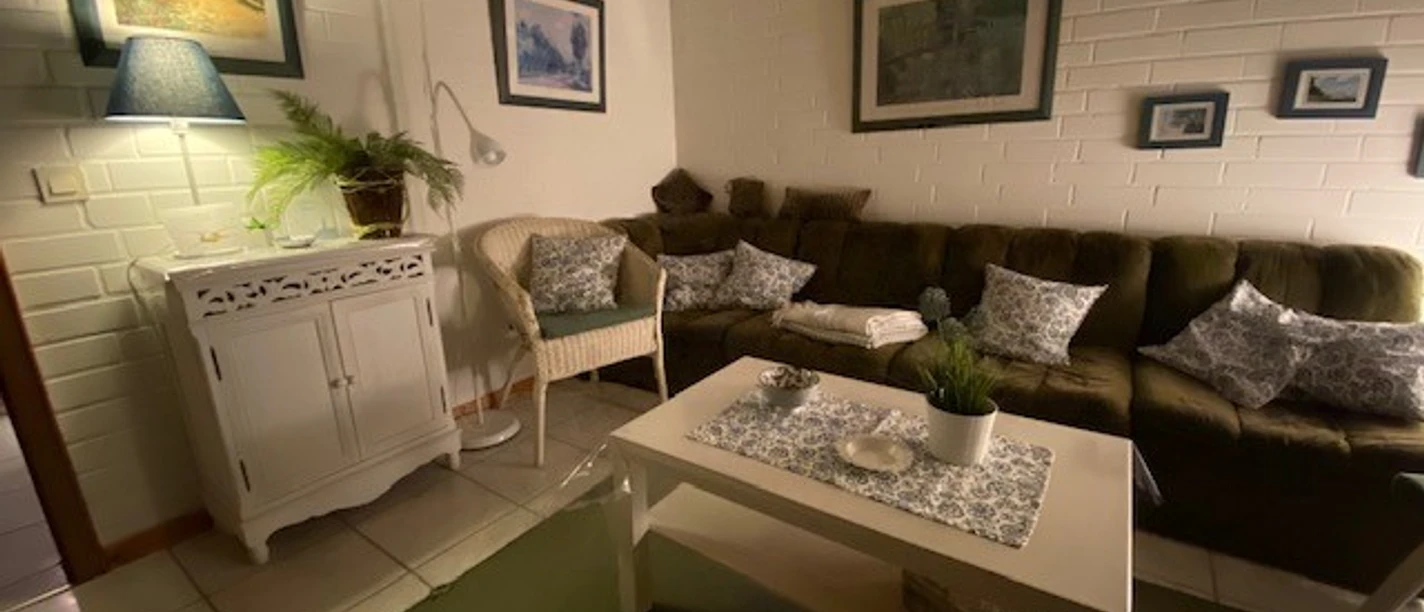 Gemütliches Wohnzimmer mit grüner Couch, weißen Möbeln und stimmungsvoller Beleuchtung.