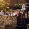 Gruppe lauscht einer historischen Stadtführung am idyllischen Mühlenrad in Bad Driburg.