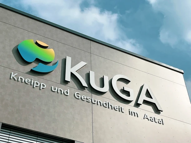 KuGA Fassade des Gesundheitszentrums KuGA mit modernem Logo und Schriftzug unter blauem Himmel.