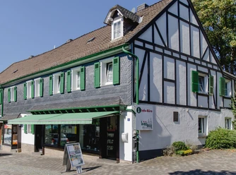 Büro Wir für Waldbröl GmbH Fachwerkhaus mit grün-weißen Fensterläden, beherbergt ein Tourismus-Info-Büro an sonnigem Tag.