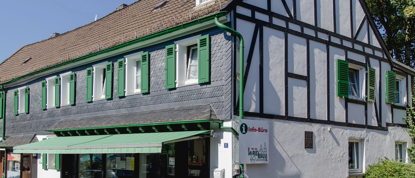 Büro Wir für Waldbröl GmbH Fachwerkhaus mit grün-weißen Fensterläden, beherbergt ein Tourismus-Info-Büro an sonnigem Tag.