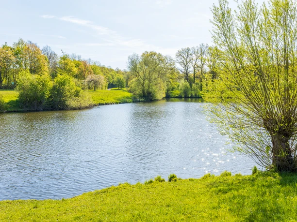 Naherholungsgebiet Große Aue Große Aue mit klarem Wasser, von Bäumen umgeben. Grüne Ufer und blauer Himmel im Hintergrund.