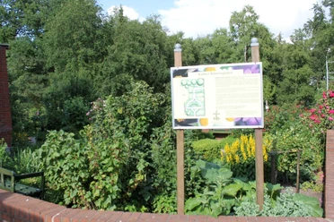Garten des Nazareners in Twist - Blick auf Käthes Bauerngarten ©Emsland Tourismus GmbH.jpg Informative Tafel inmitten eines blühenden Bauerngartens mit Sträuchern, Stauden und Bäumen.