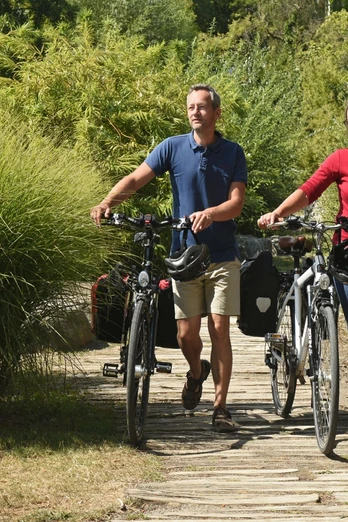 EmsRadweg-56-Themenmanagement-Radfahren-Teutoburger-Wald-F-Grawe.jpg Paar schiebt Fahrräder auf einem naturbelassenen Pfad, umgeben von grüner Vegetation.