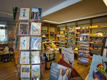 Innenansicht Die Innenansicht eines charmanten Ladens zeigt bunte Karten und Bücher auf Regalen und Ständern. Der Raum ist hell und einladend, mit einer Vielzahl an Waren.