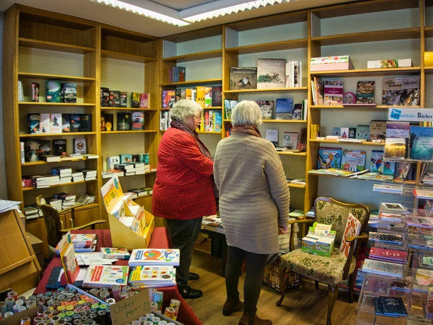Auswahl Bücher Zwei ältere Damen stehen in einem gemütlichen Buchladen, umgeben von gefüllten Bücherregalen.