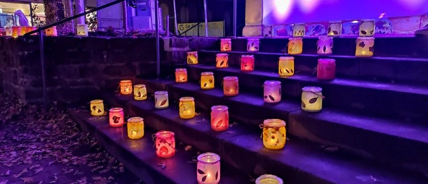 Laternen aus buntem Glas erhellen eine steinerne Treppe in farbenfrohen Lichtschattierungen bei Nacht.