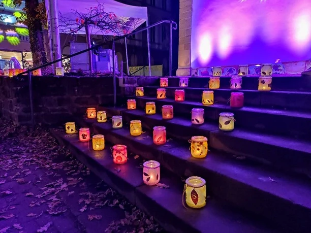 Laternen aus buntem Glas erhellen eine steinerne Treppe in farbenfrohen Lichtschattierungen bei Nacht.