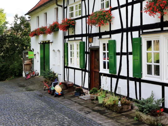 Biohof Judt im Windrather Tal bei Velbert Fachwerkhaus im Windrather Tal bei Velbert mit roten Dächern und grünen Fensterläden im ruhigen Umfeld.
