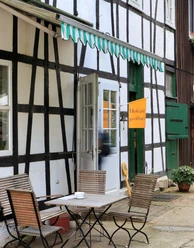 Biohof Hofcafe auf Hof zur Hellen im Windrather Tal be Velbert Traditionelles Fachwerkhaus mit Außenterrasse und geöffnetem Hofcafé im Windrather Tal bei Velbert.