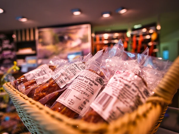 Regionale Produkte Geflochtener Korb mit verpackten regionalen Wurstwaren in einer Landschlachterei.