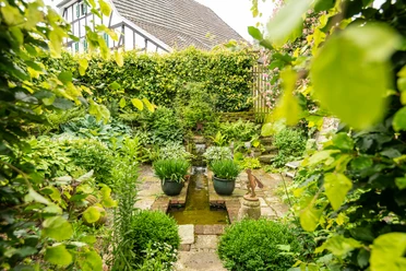 Ferienwohung Hof Tüschenbonnen Ein gepflegter, grüner Garten mit Teich und üppiger Bepflanzung in einem rustikalen Ambiente.