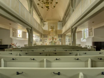 Innenansicht Innenansicht einer Kirche mit hellen Holzbänken, einem Altar und einem Kronleuchter an einer hohen Decke.
