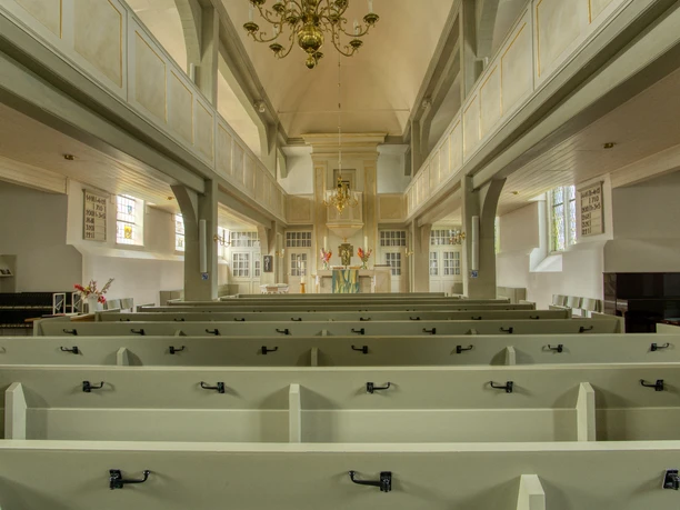 Innenansicht Innenansicht einer Kirche mit hellen Holzbänken, einem Altar und einem Kronleuchter an einer hohen Decke.