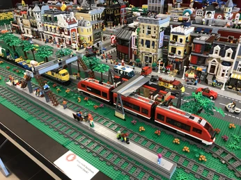 lego-bahnhof.JPG Bunte LEGO-Stadt mit Bahnhof, roten und gelben Zügen, Straßen, Figuren und detailreichen Gebäuden.