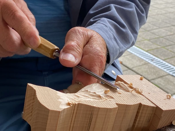 Mann schnitzt ein Stück Holz