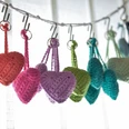 bunte Wollherzen Hobby Stübchen Handgehäkelte bunte Wollherzen hängen an Metallhaken an einer weißen Schnur.