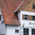Forstfrieden.jpg Hotel Forstfrieden, zweistöckiges Gebäude mit roten Dachziegeln, liegt in grüner, bewaldeter Umgebung.