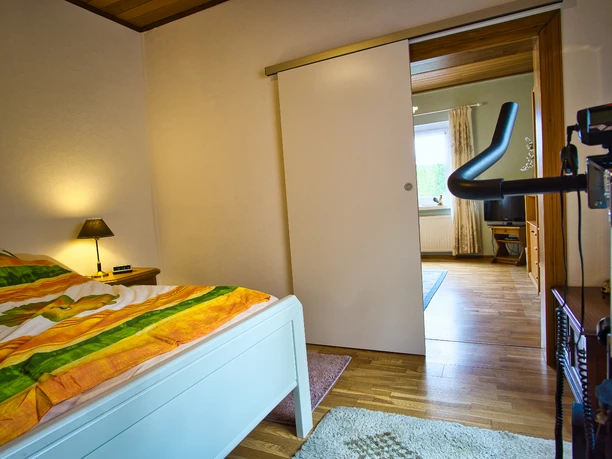 Schlafzimmer 2 Schlafzimmer mit Bett und geöffneter weißer Schiebetür, die in den Wohnbereich führt.
