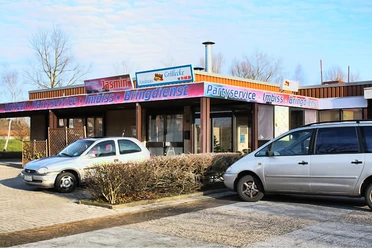 andreas-grill-ecke.jpg Zwei Autos parken vor einem Imbissgebäude namens "Andreas Grill Ecke" im Gewerbegebiet.