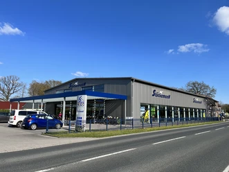 Aussenansicht von Zweirad Stückemann Außenansicht von Zweirad Stückemann mit Glasfront, Parkplatz und barrierefreiem Eingang.